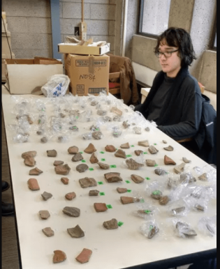 Figure 4. Bryton Smith sits with newly accession numbered objects